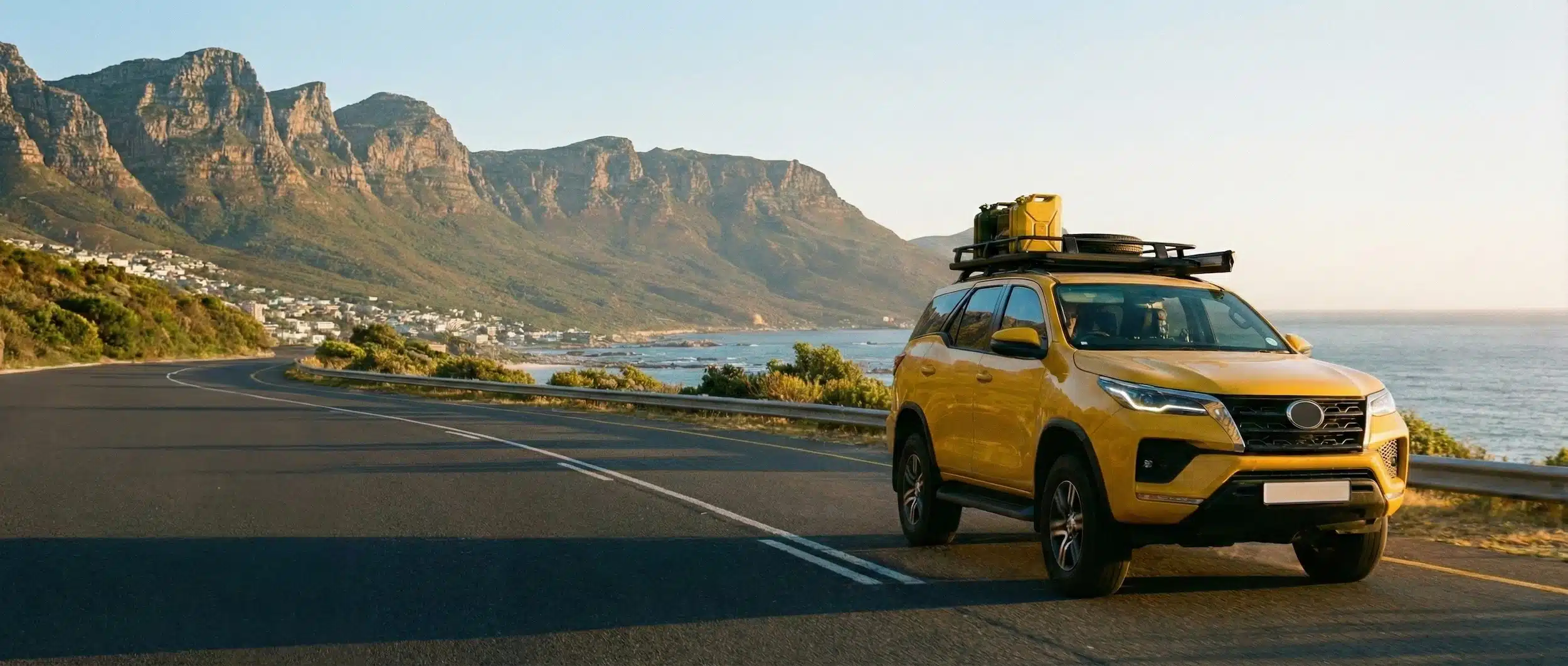 Yellow SUV driving along a coastal mountain road